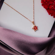 A two-sided star silver pendant chain with a rose gold finish, displayed on a purple fabric surface.